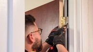 A Checkmate Fire employee carrying out repair work on a fire door hinge.