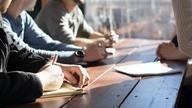 Staff in meeting take notes.