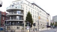 Building next to street with traffic lights in foreground.