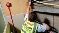 A Checkmate Fire supervisor carrying out fire stopping installation work on wall panels.