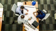 Overhead view of 3 staff members drawing up plans.