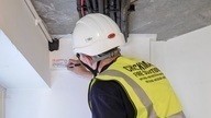 A member of the Checkmate Fire team writing a label on a wall as part of the inspection process.