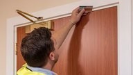 A Checkmate Fire fire door installer using a ruler to check the top of a door.