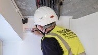 A Checkmate Fire employee adding a label to a ceiling as part of fire stopping installation work.