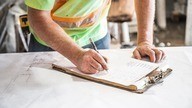 A Checkmate Fire employee writing on a clipboard as part of a fire risk assessment. 