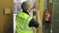 A Checkmate Fire inspector holding a fire door and conducting a fire door survey.