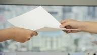 2 hands pass piece of paper